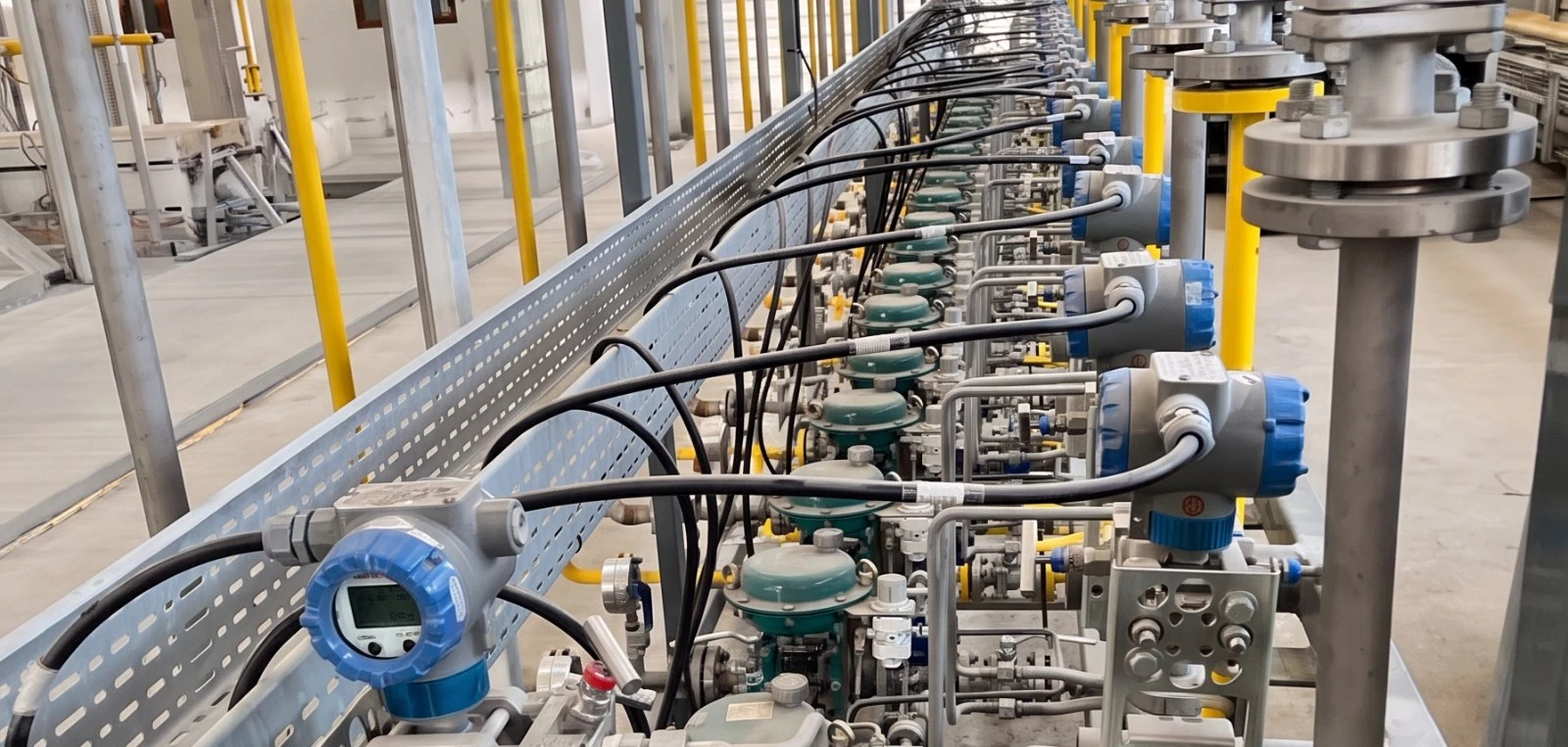 Row of gas metering points with manifolds and transmitters serving furnace burners