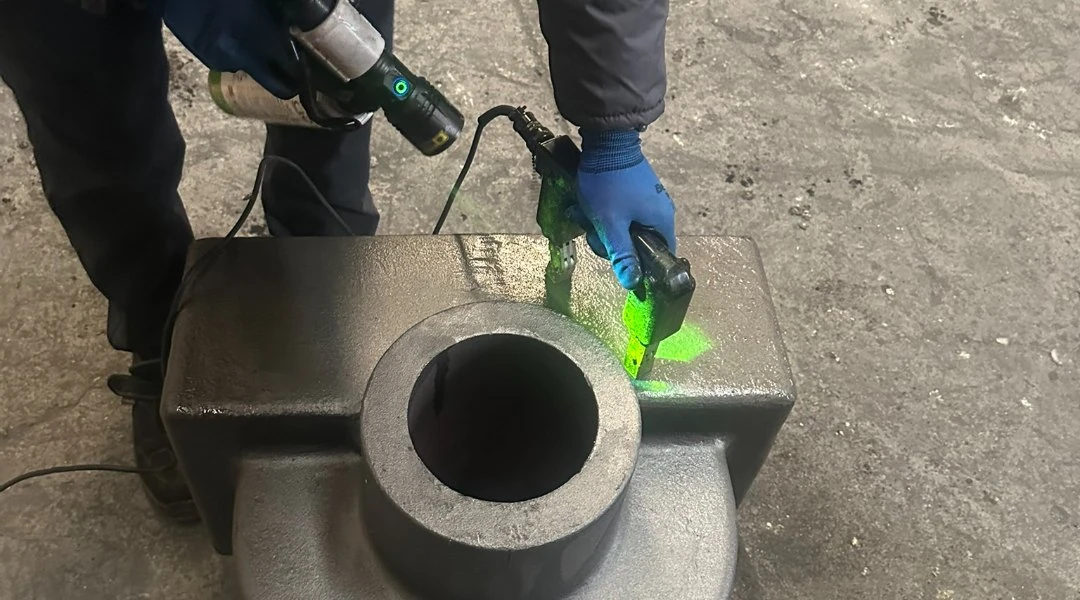 Magnetic particle inspection of a cast fitting body under UV light